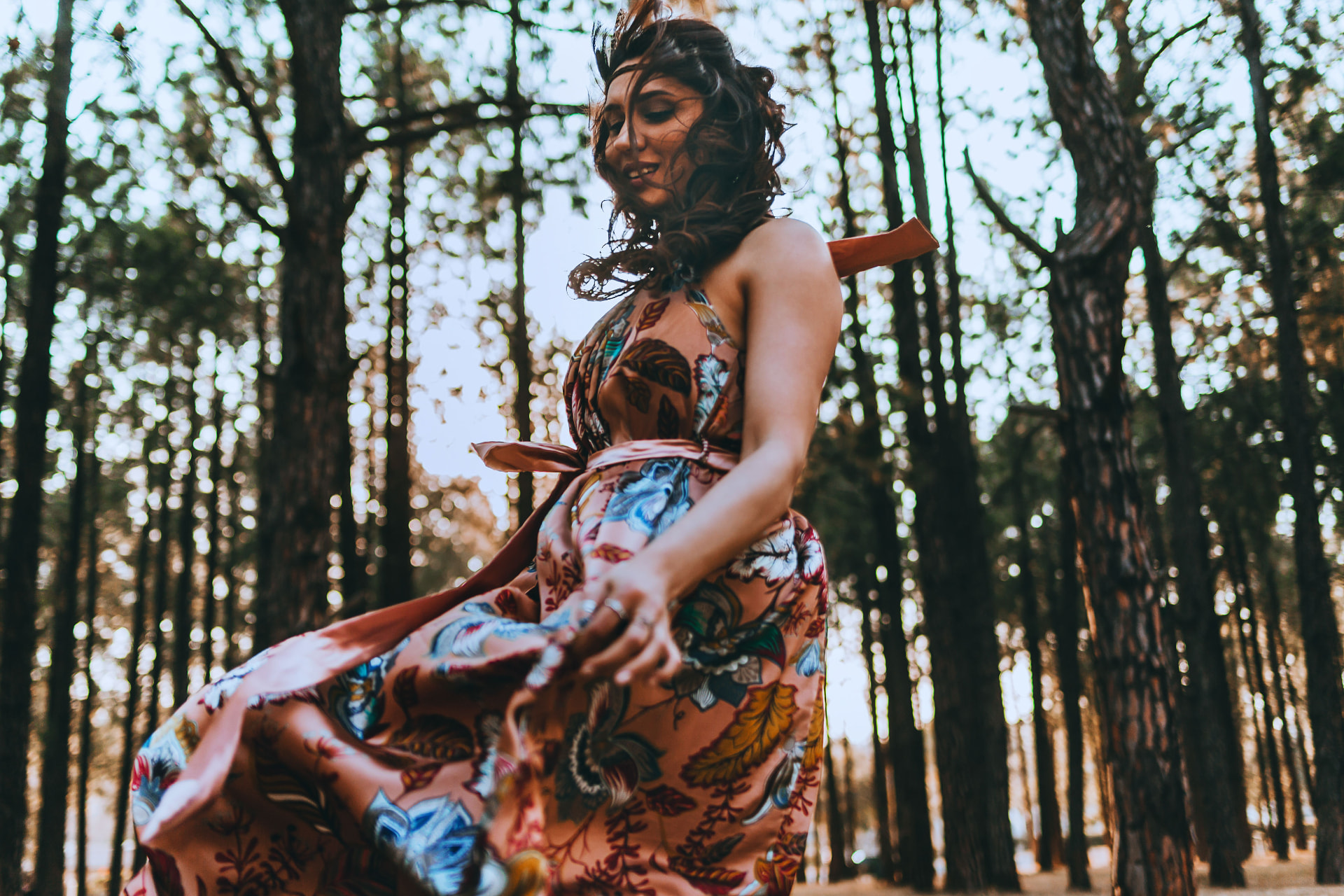 Noa twirling in a flowing floral dress in a sunlit forest